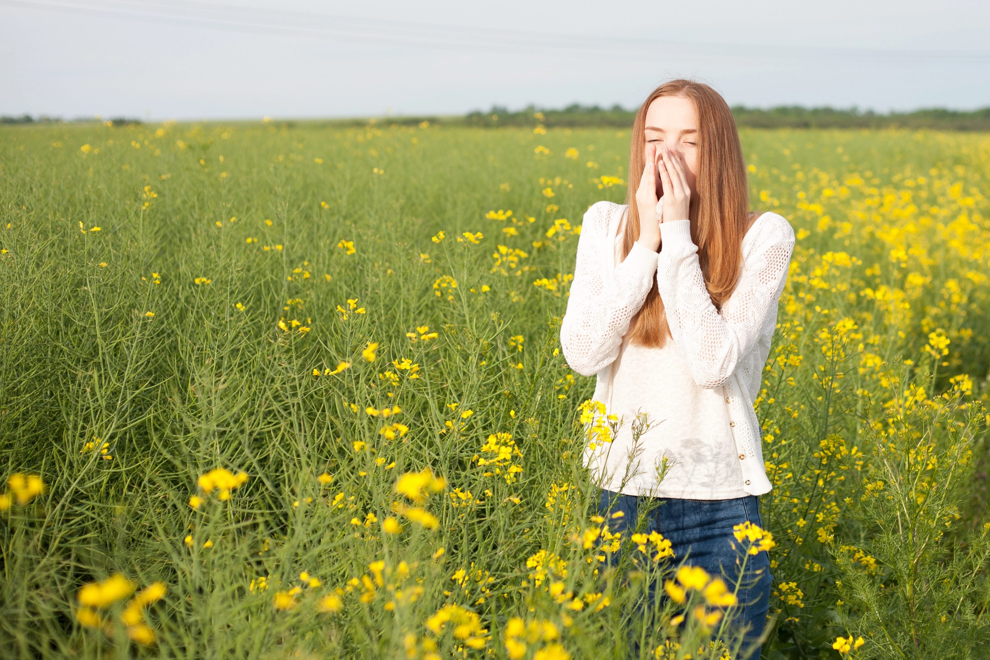 Woman sneezing in a field of flowers